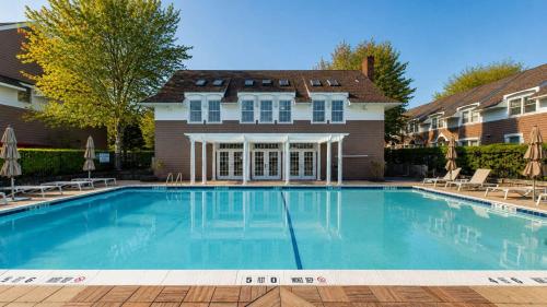 a large swimming pool in front of a house at Hampton Bays Townhouse - Pool Beach Access in Hampton Bays