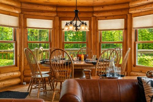 a dining room with a table and chairs and windows at Fiddler Lake Resort - Deer 79 in Mille-Isles
