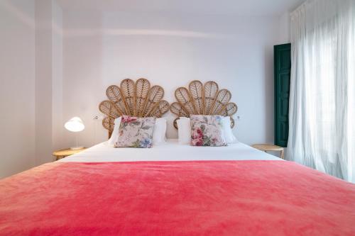 a bedroom with a large bed with a red blanket and pillows at Apartamentos El Escudo Centro in Ribadesella
