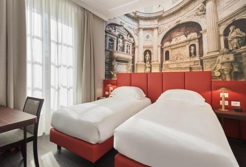 two beds in a room with a church mural at Palazzo Caracciolo Naples in Naples
