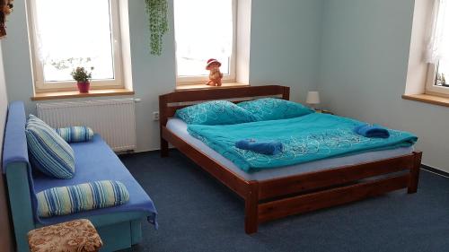 a bedroom with a bed with blue sheets and windows at Ala ubytovani in Josefŭv Dŭl
