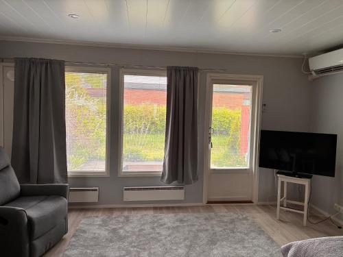 a living room with two windows and a flat screen tv at Koivukuja in Köyliö