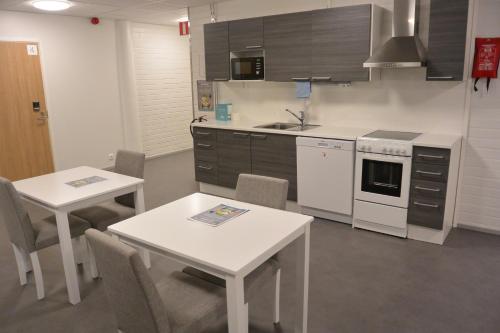 a kitchen with two tables and a stove top oven at Forenom Aparthotel Raahe in Raahe