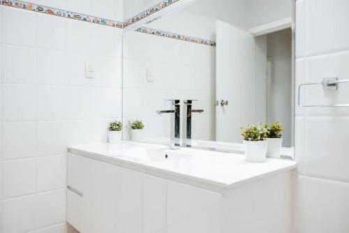 a white bathroom with a sink and a mirror at Iconic Escape Nowra in Nowra