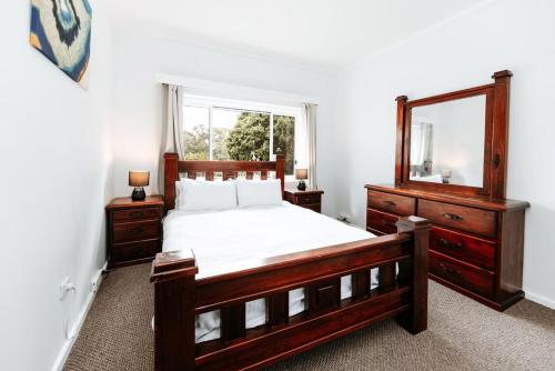 a bedroom with a wooden bed and a mirror at Iconic Escape Nowra in Nowra