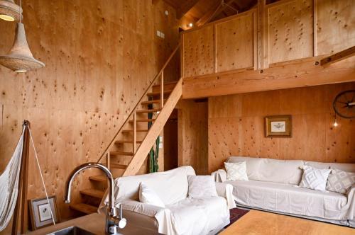 a living room with white couches and a staircase at anandahの宿 in Miyazaki