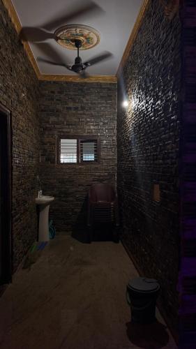 a room with a ceiling fan and a brick wall at Yashaswi Hilldeck in Sondekoppa