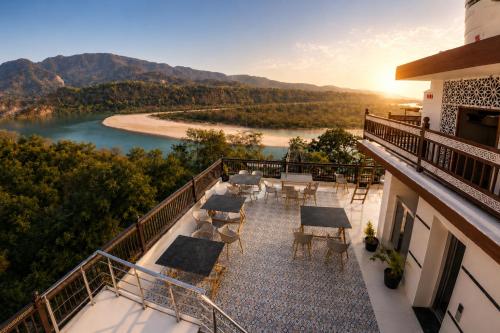 a balcony with tables and chairs and a view of a river at Hotel The Montara Near Ganga Ghat in Rishīkesh