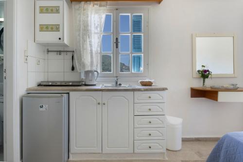 a white kitchen with a sink and a window at Yiorgo's Studios in Kalymnos