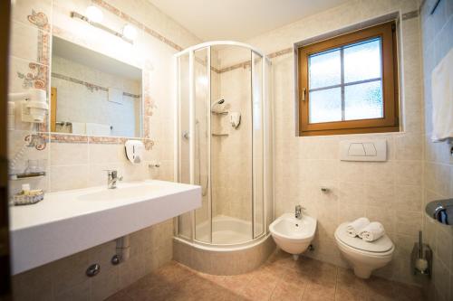 a bathroom with a sink and a shower and a toilet at Turmhotel Gschwendt in Valle Di Casies