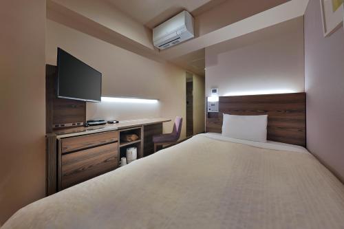 a bedroom with a large bed with a tv on the wall at Keio Presso Inn Ikebukuro in Tokyo
