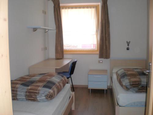 um pequeno quarto com 2 camas e uma janela em Anna Apartment em Pozza di Fassa