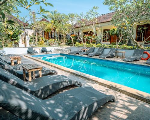 a swimming pool with chaise lounge chairs next to a house at The Tanis Beach Resort Nusa Lembongan in Nusa Lembongan
