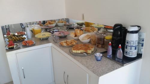 a kitchen counter with many dishes of food on it at Hotel Piratini in Curitiba