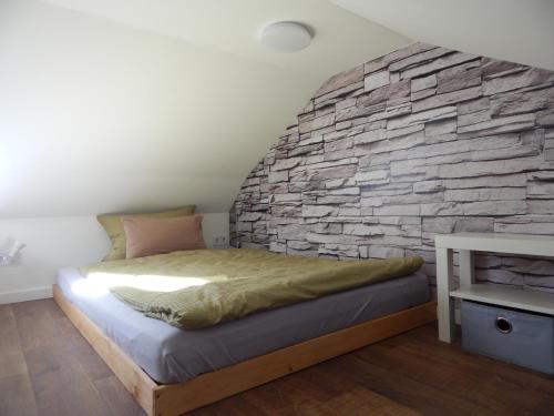 a bedroom with a stone wall and a bed at JundJ Ferienwohnungen in Buzsák