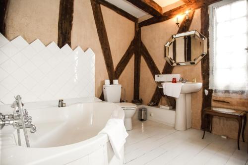 een badkamer met een bad, een toilet en een wastafel bij Villa La Roseraie avec accès piscine Hôtel La Roseraie in Montignac
