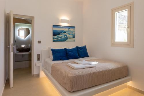 a bedroom with a bed with blue pillows and a window at Villa Karras - Sea & Mountain View in Perissa