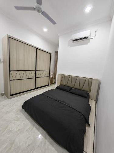 a bedroom with a black bed and a fan at UMRA Homestay in Kampong Padang Kemunting