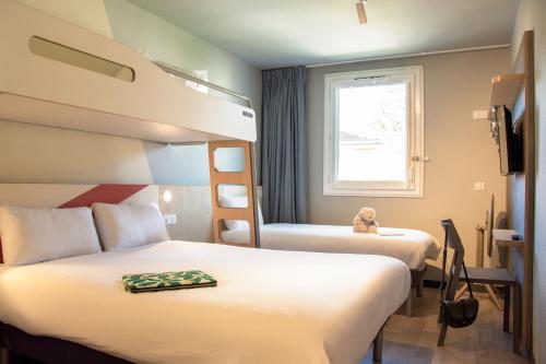 a hotel room with two beds and a window at ibis budget Bordeaux Sud in Villenave-dʼOrnon