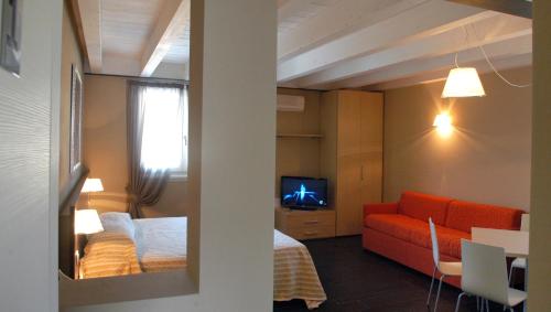 a room with a bed and a couch and a television at Affittacamere Sale e Pepe in Cavaion Veronese