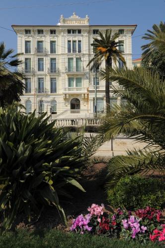 a building with palm trees and flowers in front of it at Hotel De Paris Sanremo in Sanremo