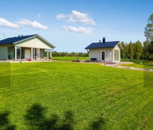 a house with a large green lawn in front of a house at Paris Beach in Saarijärvi