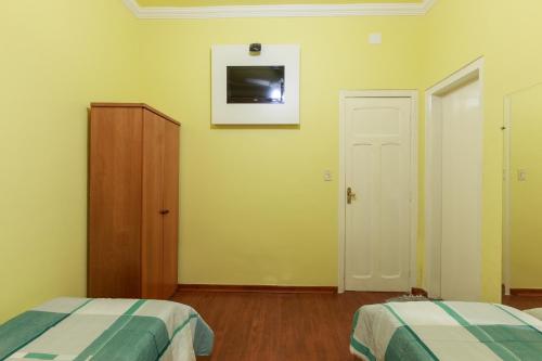 a bedroom with two beds and a tv on the wall at Hotel Boa Viagem in Belo Horizonte