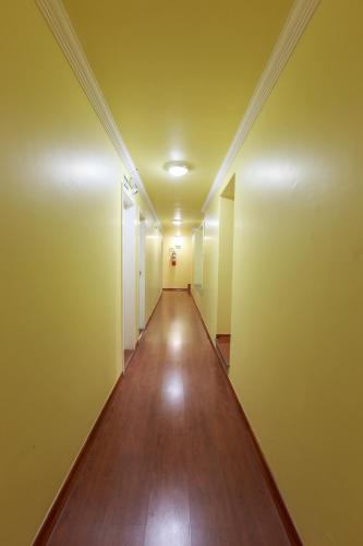 an empty hallway in an apartment with yellow walls and wooden floors at Hotel Boa Viagem in Belo Horizonte
