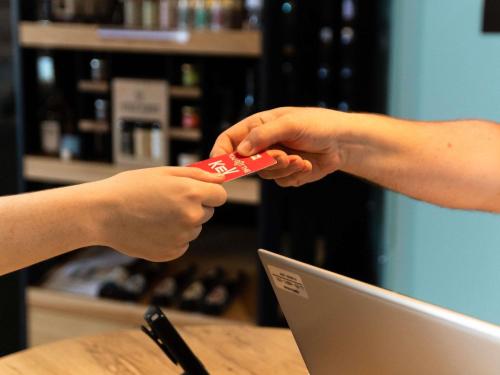 two people holding a remote control in front of a laptop at Hotel ibis Narbonne in Narbonne
