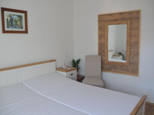 a bedroom with a white bed and a mirror at Ferienwohnung Selkeblick in Falkenstein