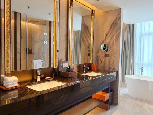 a bathroom with two sinks and a tub and a large mirror at Sheraton Tengzhou in Zhaozhuang