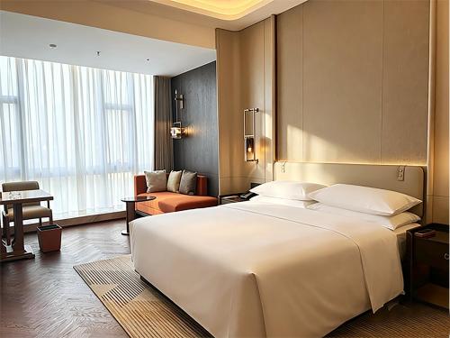 a bedroom with a large white bed and a living room at Sheraton Tengzhou in Zhaozhuang