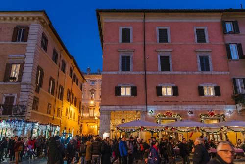 a crowd of people walking in a street in front of buildings at Rhea Silvia Luxury Navona in Rome