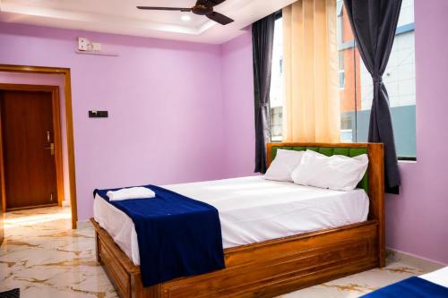 a bedroom with a bed with purple walls and a window at SRL Grand Residency in Tirupati