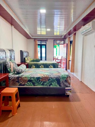 a room with two beds and a table at Marlynto Surf Camp in Hilibotodane