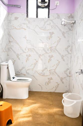 a bathroom with a toilet and a white marble wall at SRL Grand Residency in Tirupati