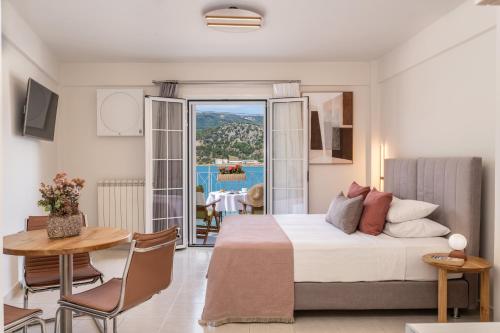 a bedroom with a bed and a table and a balcony at Argostοli Bay Apartments in Argostoli
