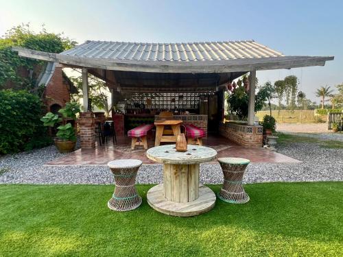 a patio with a table in the grass at Driftwood and Jolie cottages in Sam Roi Yot