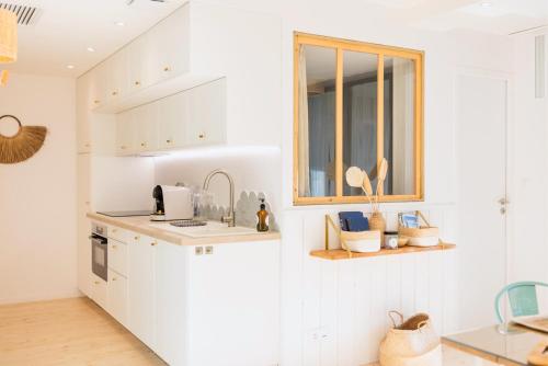 a kitchen with white cabinets and a window at Appart'Hôtel & Spa "Les Voiles" Belle Île en Mer in Carnac