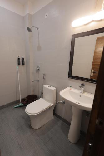 a bathroom with a toilet and a sink and a mirror at Maktain Glance in Dehradun
