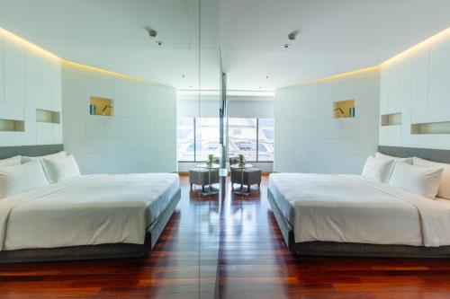 two beds in a large room with white walls at LiT BANGKOK Hotel in Bangkok