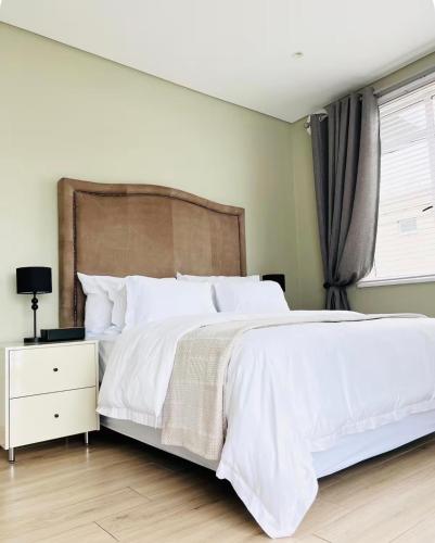 a bedroom with a white bed and a window at Premier Residence in Windermere in Durban