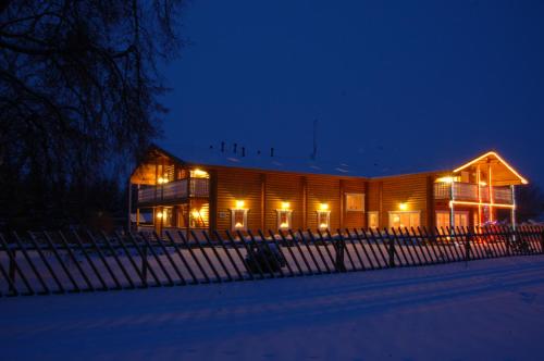 a wooden building with lights in the snow at night at Külalistemaja Vehendi Motell in Vehendi
