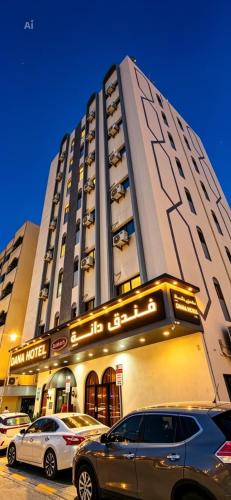 a large building with cars parked in front of it at DANA HOTEL-Clock Tower Sharjah in Sharjah