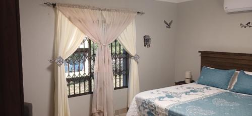 a bedroom with a bed and a window with curtains at Inyati Guest House in Marloth Park