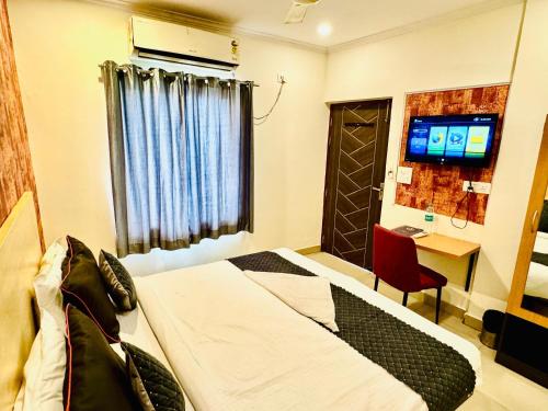 a hotel room with a bed and a desk and a television at Hotel Diamond View in Greater Noida