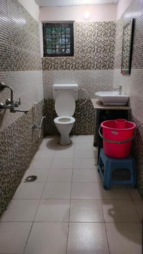 a bathroom with a toilet and a sink and a bucket at Sheetal Resort and Restaurant in Rudraprayāg