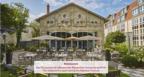 a restaurant with tables and umbrellas in front of a building at H4 Hotel Residenzschloss Bayreuth in Bayreuth