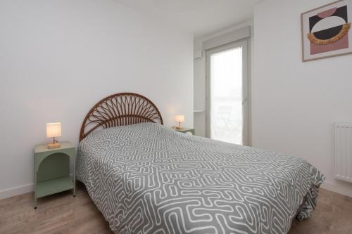 a bedroom with a bed and two tables with lamps at La belle étoile - 4 pers - balcon in Vannes