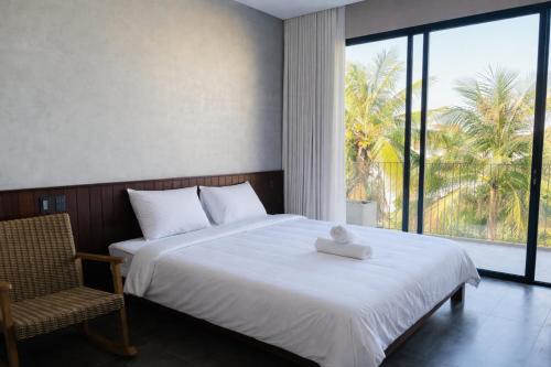 a bedroom with a bed and a chair and a window at HOA GIO Boutique stay in Hue